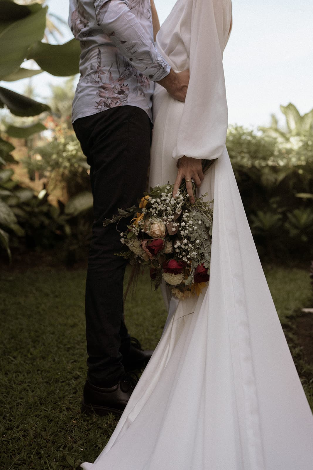 A close detail of a wedding bouquet and flowing white dress