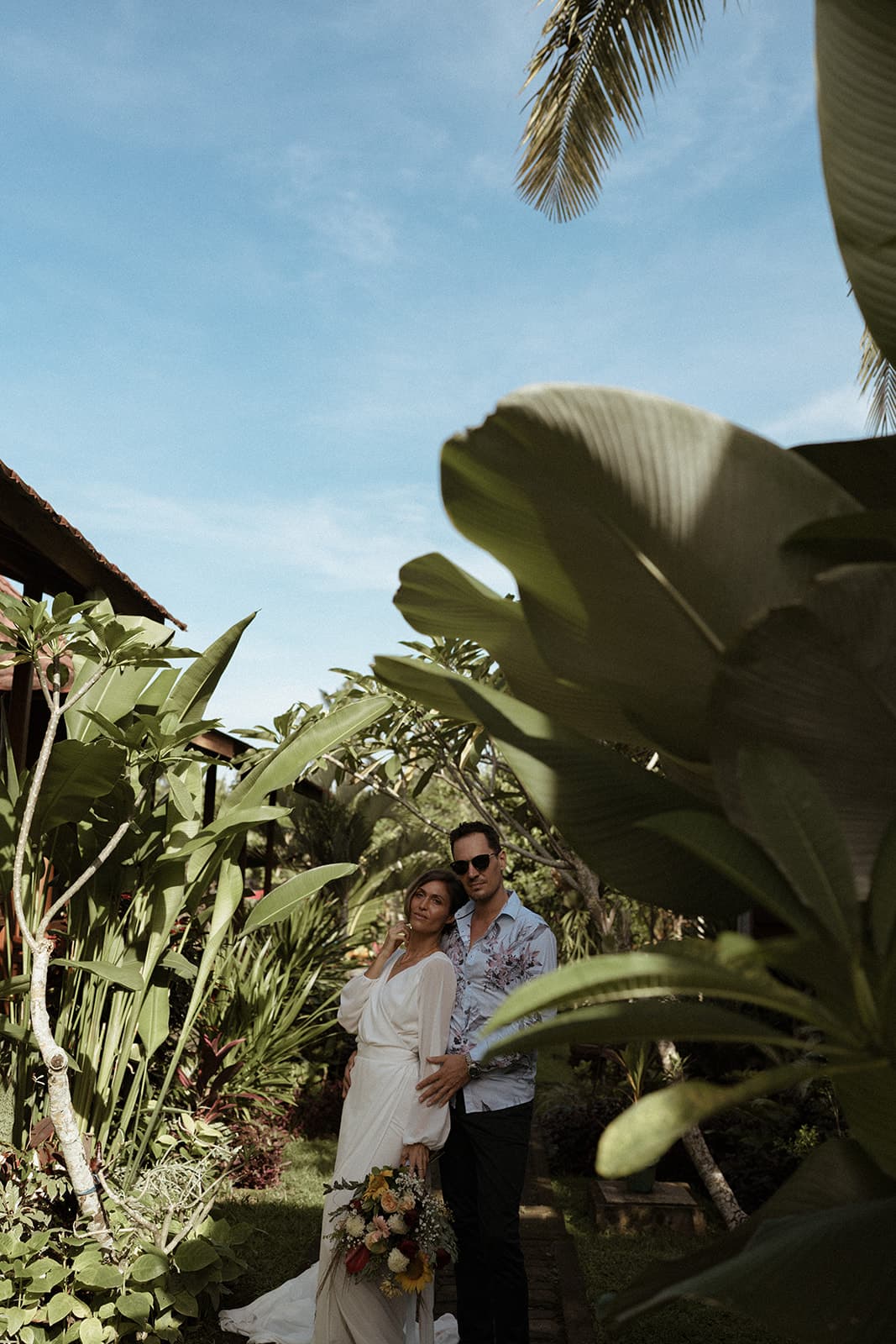 A couple standing together in a tropical garden setting