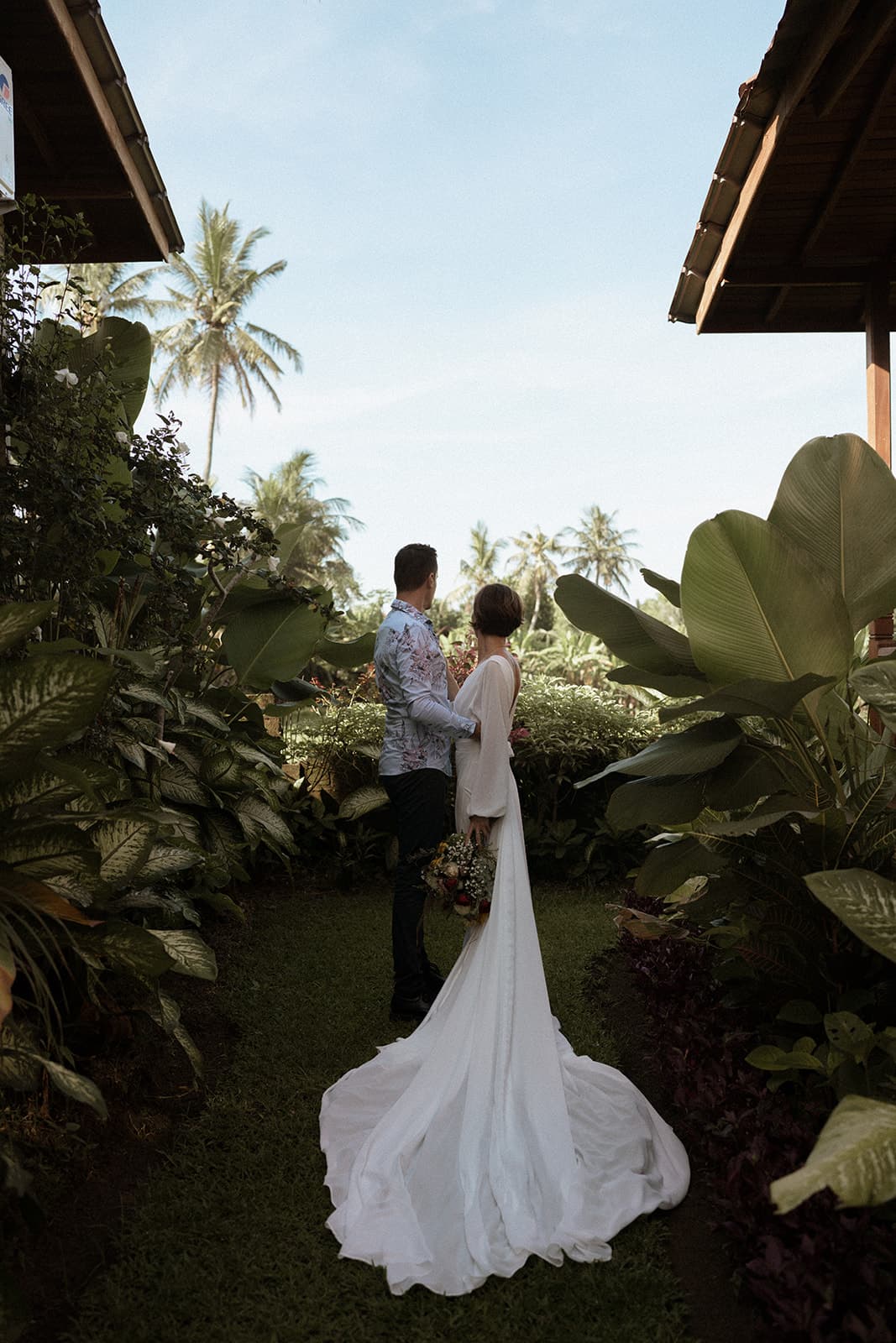 A couple looking out across palms from a lush garden walkway