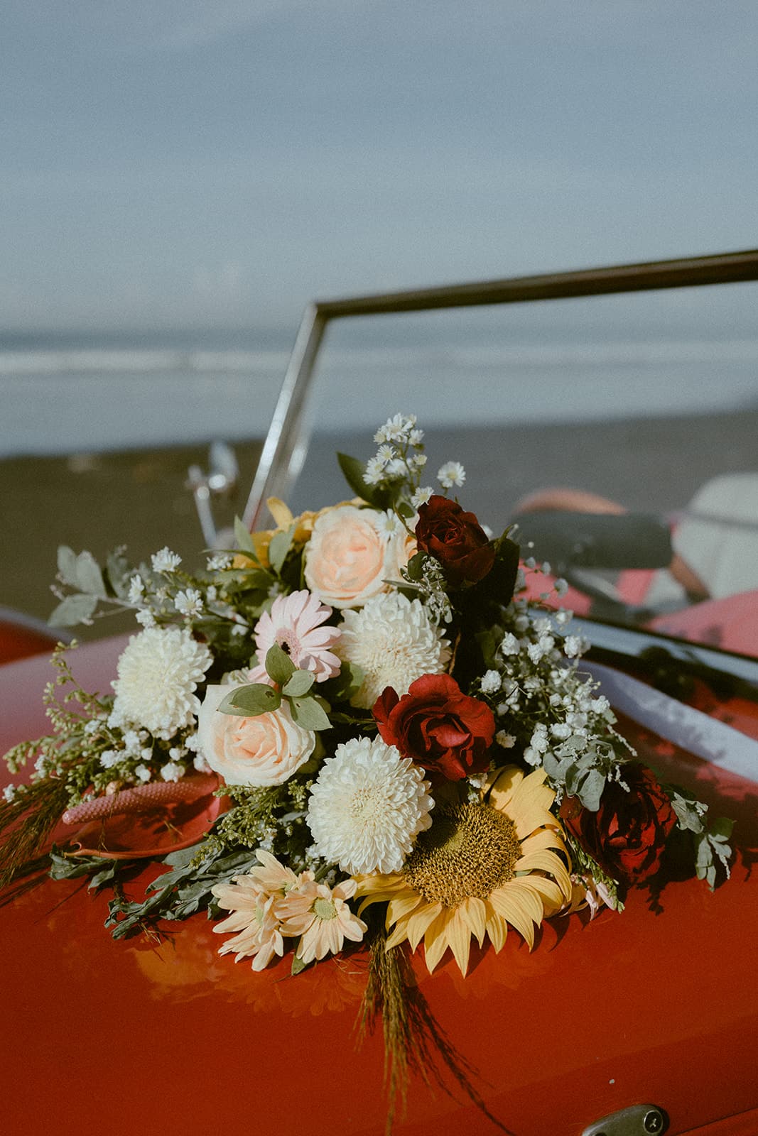 Wedding florals arranged against a vintage red car